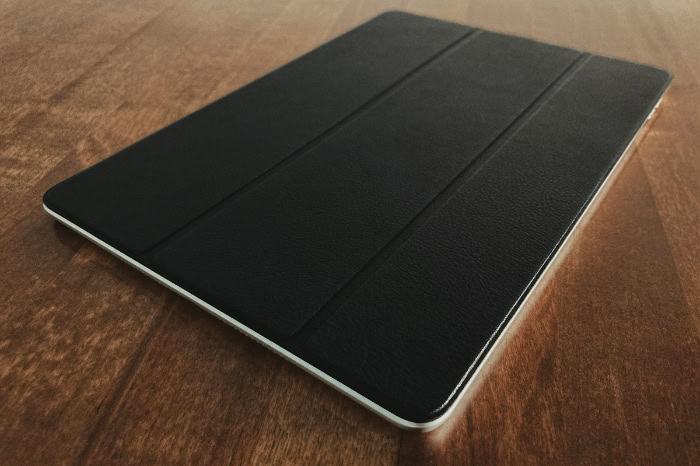 Closed iPad with black folio case on wooden table