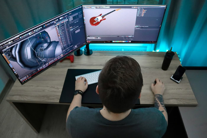 Designer creating 3D models on dual monitors
