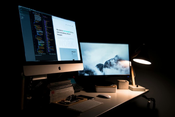Dual monitor desktop with coding and design workspace