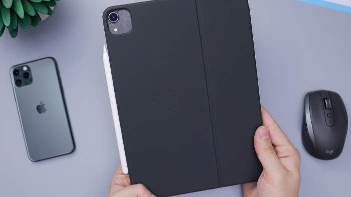 Hand holding iPad with black case and Apple Pencil