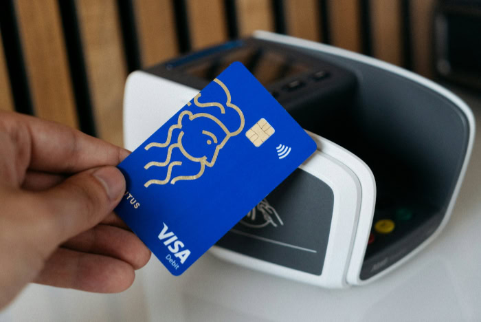 Hand tapping Visa card on contactless payment reader
