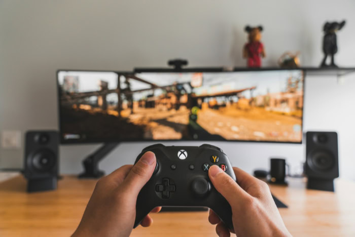 Hands holding Xbox controller in front of monitor