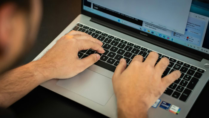 Hands typing on a laptop keyboard