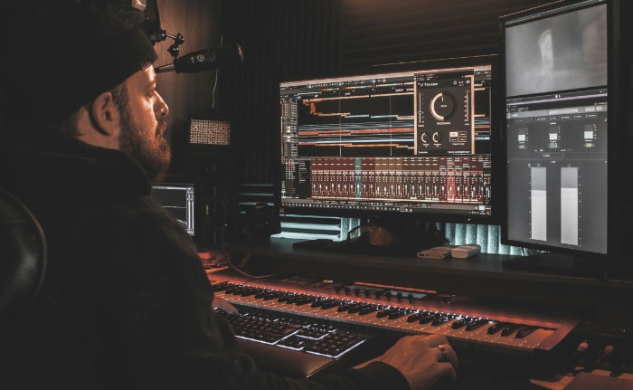 Music producer at dimly lit workstation with DAW software