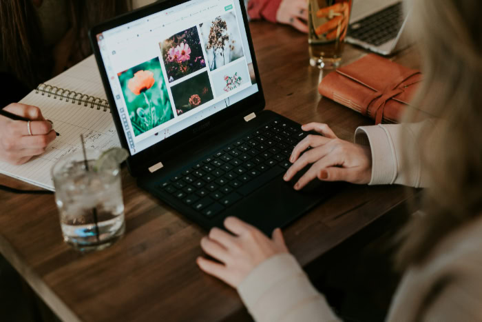 Person browsing images on laptop at shared desk