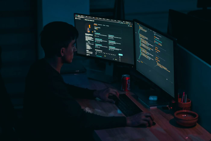 Programmer working at dual monitors in dark office